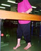 並行棒を使って、かかとを付けて歩くイメージを訓練している